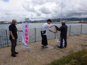 釣り客に啓発物品を配布する公立環境大学の生徒達2